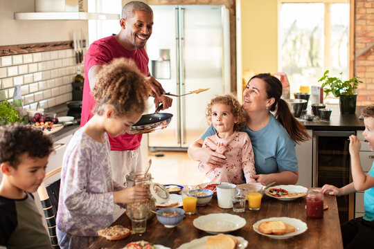 Parents cooking breakfast with children in the home kitchen