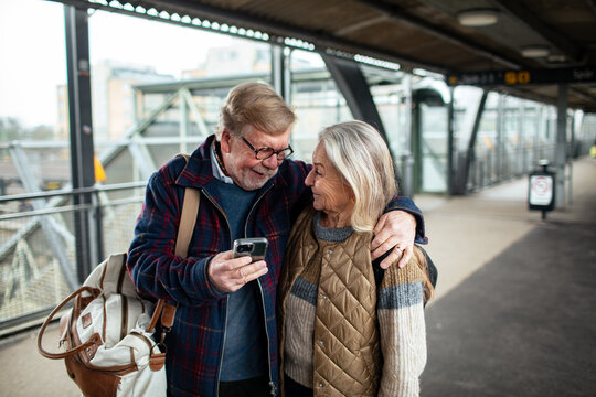 Senior couple using smartphone at train station