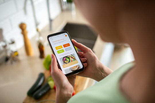 Woman using recipe app on smartphone in kitchen