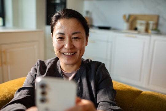 Smiling woman video calling on smartphone at home