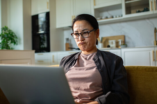 Frustrated woman working on laptop in home kitchen
