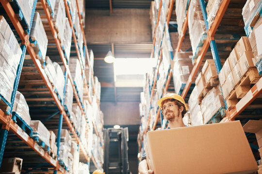 Warehouse worker carrying box in distribution center aisle