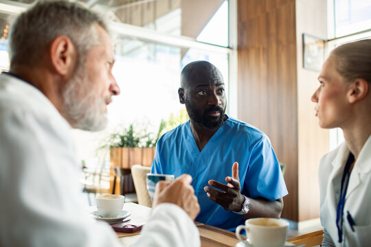 Medical team discussing cases over coffee in hospital cafeteria