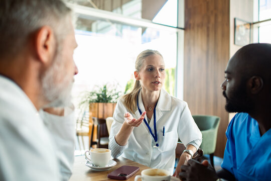 Doctors discussing patient case over coffee in hospital cafeteria