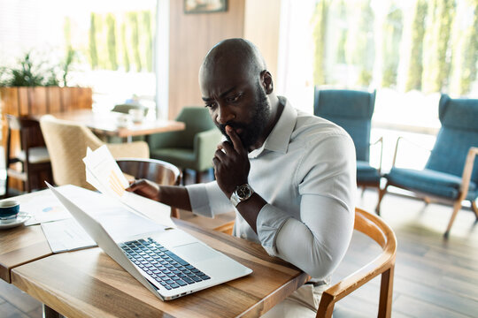 Focused businessman reviewing financial charts on laptop in cafe