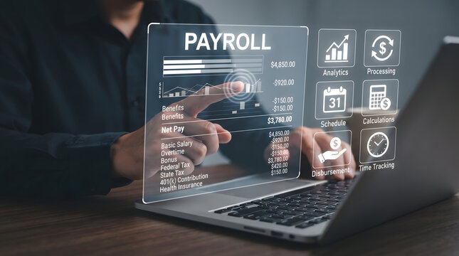 Man Working on Laptop with Transparent Payroll Interface on Screen in Dark Office Setting