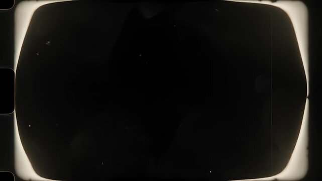 White film frame edges glowing and fading like celluloid burn on black background.