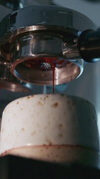4K Pouring coffee stream from professional machine in cup. Barista man making double espresso, using filter holder. Flowing fresh ground coffee. Drinking roasted black coffee in the morning.	
