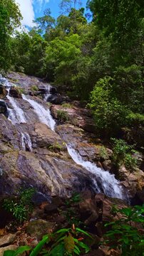 Scenic view of Ngao Waterfall, one of southern Thailand most beautiful waterfalls, flowing through dense green forest beneath the Khao Nom Sao mountain range in Ranong Province. high and wonder