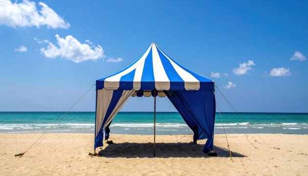 Blue and white striped tent on a sandy beach under a bright blue sky