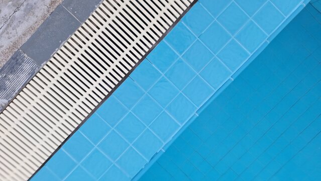 Blue swimming pool tiles with drainage grating background pattern