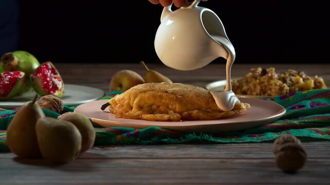 Woman's hand pouring traditional walnut sauce over a chile en nogada
