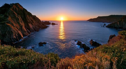 Obraz premium Sunset over ocean cove with rugged cliffs and golden light reflection on water