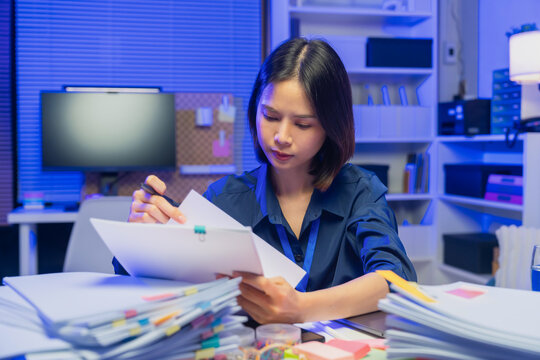Young Asian businesswoman reviewing documents while working in office, business administration and paperwork concept.
