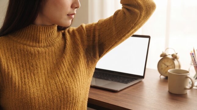 Close up of woman raising arm holding head while working at laptop desk showing fatigue or armpit area