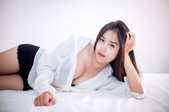 Young Asian woman lying down on bed, looking to the camera