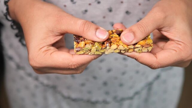 Hands are preparing to break a nut bar made with nuts and honey