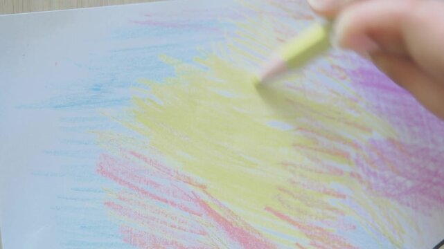 Drawing with colored pencils on paper at a table
