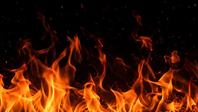 Close-up view of vibrant orange flames dancing against a dark, black background with tiny sparks.