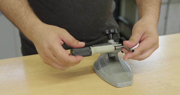 Technician measuring a metal component with a micrometer, demonstrating precision measurement and quality control in manufacturing.