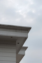 White building cornice with decorative molding and recessed ceiling lights against an overcast sky. © Okta