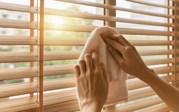 Cleaning Wooden Blinds with Careful Hands to Maintain a Beautiful Home Environment in Natural Light