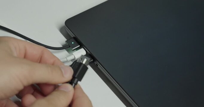 Person trying to connect another USB device to a laptop with all ports already occupied, illustrating limited connectivity and insufficient USB ports.