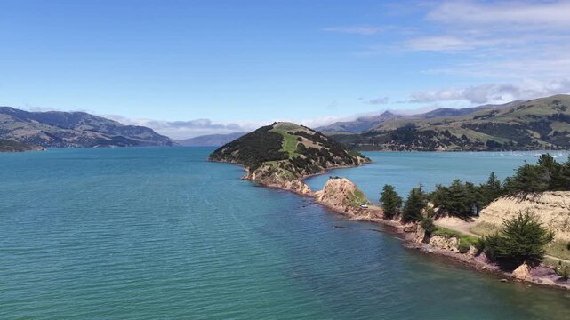 An aerial view of the Onawe Peninsula in Akaroa Bay, New Zealand. The calm, blue water on a sunny day