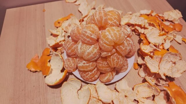 Fresh Peeled Mandarins Arranged on Plate with Scattered Citrus Peels Indoors