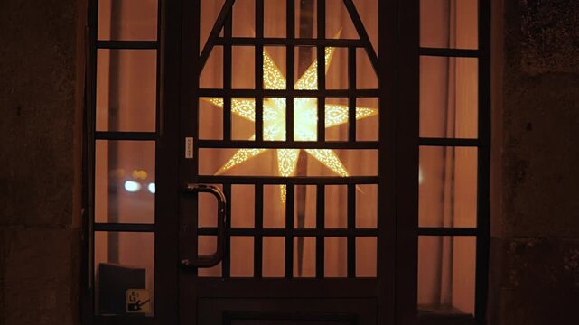 Festive lighting fills window, reflections of passing traffic create atmosphere