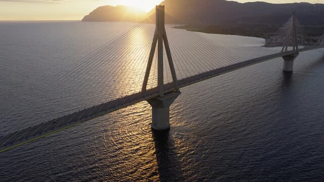 Rio-Antirrio Bridge at sunset over Gulf of Patras near Patra Greece, drone ascend medium establishing, stunning establishing aerial