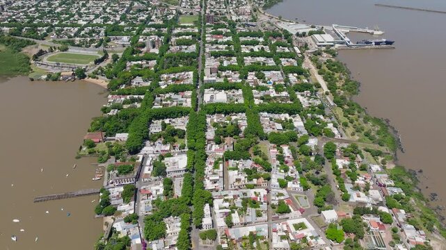 Aerial panoramic overview of Colonia del Sacramento beside Rio de la Plata Uruguay, drone backdrop of urban grid outlined with trees