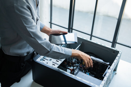 Asian IT engineer holding tablet using AI helping fix pc case