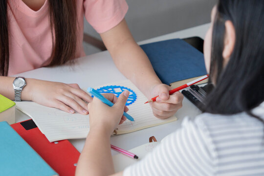 Two Asian girl with books on table doing homework together at home
