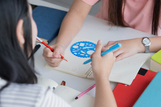 Two Asian girl with books on table doing homework together at home
