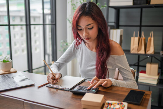 Woman managing small business accounts and recording sales revenue and expenses business income financial management entrepreneurship .
