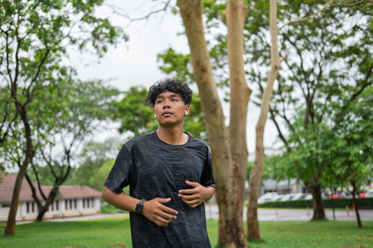 African American mixed race man jogging in green city park for wellness active and feel good lifestyle.