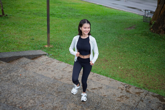 Asian Gen Z woman jogging in green urban park for wellness fitness and active city lifestyle