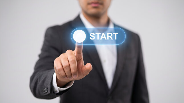 Initiation Button Pressed A businessman in a dark suit points a finger towards a glowing blue START button symbolizing the beginning of a new endeavor or project