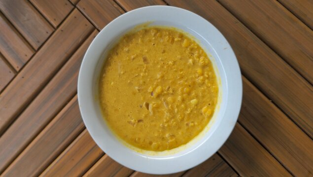 Topdown bowl of fresh homemade delicious Sri Lankan lentil curry dhal cuisine presented on rustic wooden table