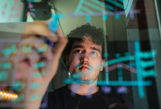 Man analyzing data and visualizing graphs on transparent screen