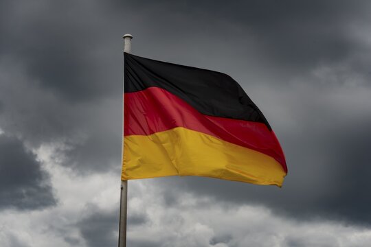 Germany flag in the wind in front of dark clouds, black-red-gold, Berlin, Germany