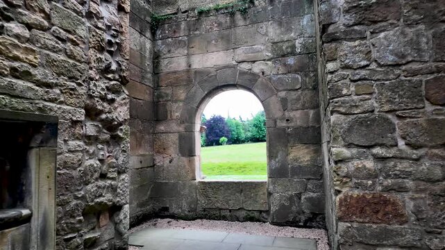 Interior of an ancient stone castle ruin with a view of the green landscape from an arched window. push forward shot