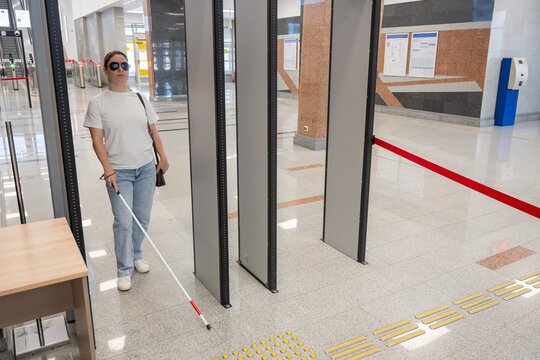 A blind woman walks through a metal detector. 