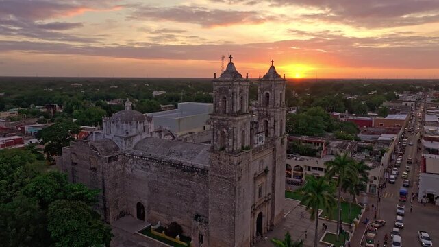 Aerial view over the convent rooftop and colonial town of Valladolid, Yucatan, Mexico, glowing under a warm golden-hour sky at sunset.