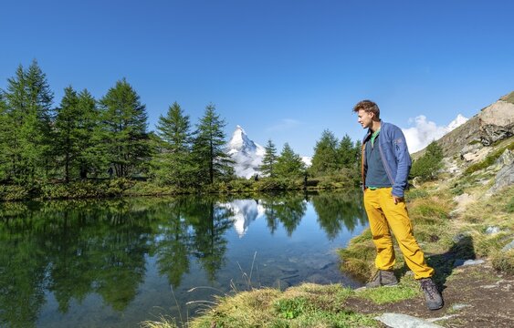 Hiker on Lake Grindij, snow-covered Matterhorn reflected in the lake, 5 lake hike, Valais, Switzerland