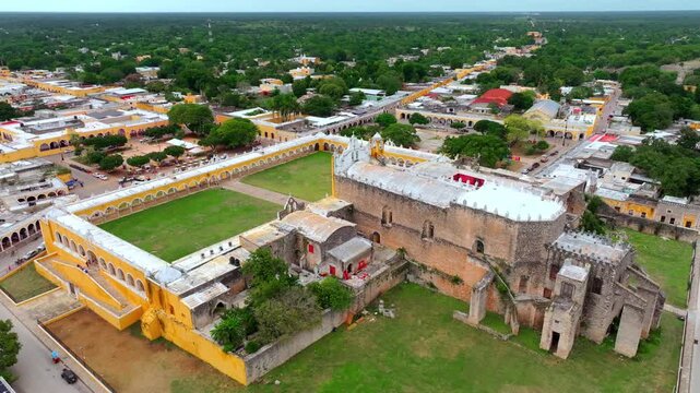 Aerial view of the vast arcaded atrium of the San Antonio de Padua convent in Izamal, Yucatan, Mexico, its yellow galleries surrounding a green court.
