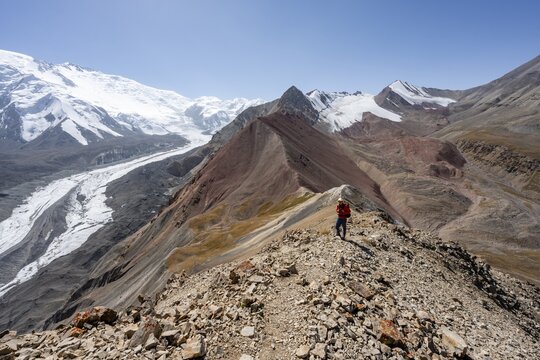 Mountaineer at Traveller's Pass with view of impressive mountain landscape, high mountain landscape with glacier moraines and glacier tongues, glaciated and snow-covered mountain peaks, Lenin Peak, Trans Alay Mountains, Pamir Mountains, Osh Province, Kyrgyzstan