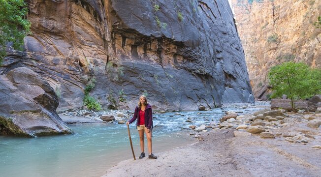 Hiker standing next to river, Zion Narrows, narrow of the Virgin River, steep faces of Zion Canyon, Zion National Park, Utah, USA