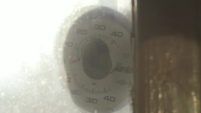 Soviet era thermometer displays minus one degree beside frosty apartment window